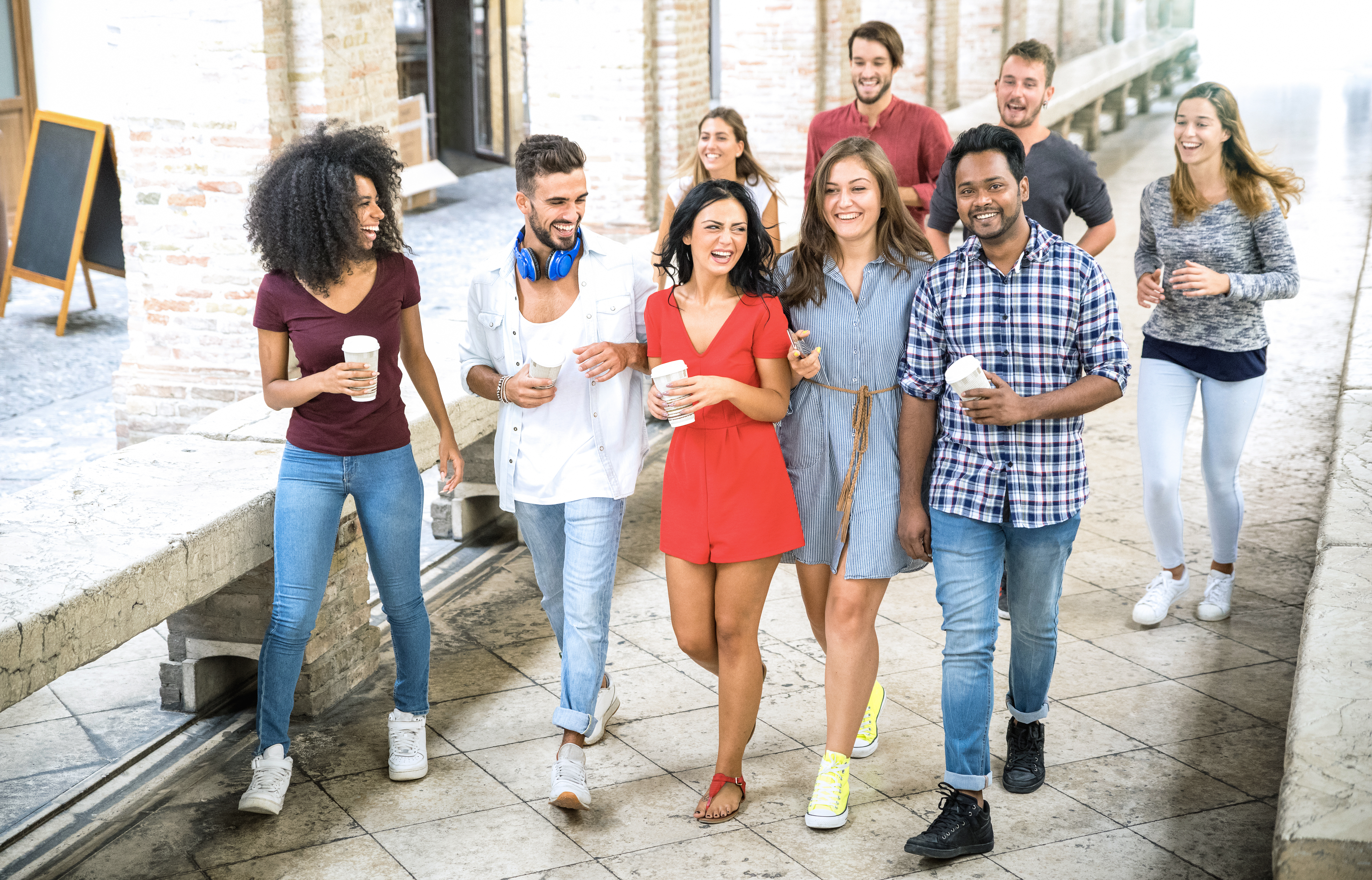 Multiracial friends group walking in city center - Happy guys and girls having fun around old town streets